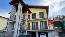 2-story yellow building with wooden roof, balconies, and a garage on the ground floor.