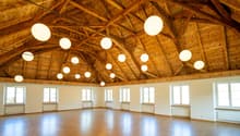 large open space, wooden floor, wooden ceiling, hanging lamps, windows