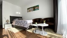 Bedroom with bed, 2 chairs, white table, white nightstand, lamp, carpet, picture on wall
