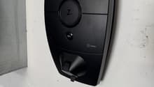Black electric vehicle charger mounted on white wall, branded Zaptec