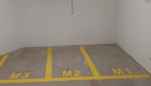 Concrete floor, labeled parking spaces M1, M2, M3, power outlets on the wall