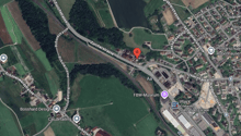 Area shows a road with green areas, buildings, a small lake, a red marker and street labels