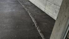 An empty concrete garage with a grey parking area and concrete walls. There is an access point with a white electrical socket
