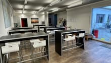 modern office room with black tables, white chairs, wooden floor, glass door, white walls, ceiling lights