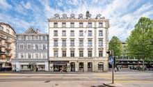 5 story white building with many windows, street level cafes