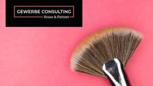 The image shows a black and white logo for 'GEWERBE CONSULTING Kruse & Partner' against a bright pink background. There is also a large makeup brush visible in the foreground.
