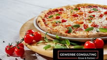 Whole pizza with tomatoes and basil on a plate with some cherry tomatoes around it.