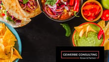 Mexican food such as tacos, salsa, chips, guacamole, soup, vegetables, garlic and chili peppers