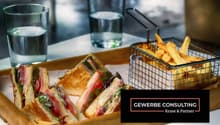 A wooden tray with sandwiches and french fries, two glasses of water, and a basket of fries