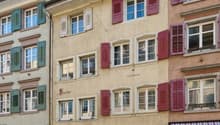 2-story building, red shutters, large windows, ground floor storefronts, cobblestone street