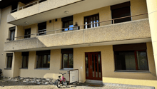 Two-story building, with multiple balconies, front door, pink bicycle parked.
