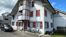 2 story house, white exterior, red shutters, balcony, car parked in front