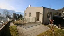 Raised single story house, concrete floor, glass entrance, large windows, pathway