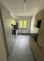 modern kitchen with white cabinets, black countertops, tiled floor, window with view