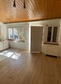 empty room, wooden floor, white walls, wooden ceiling, kitchen area with sink, cabinets, and windows