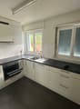 modern kitchen with white cabinets, black countertops, stainless steel appliances, double sink, and a window with blinds