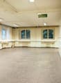 Large open room with high ceilings, arched windows, and a 'Not ausgang' (emergency exit) sign. The room has a concrete floor and appears to be a multipurpose space, possibly used for events or activities.