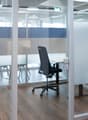 glass office space, open area with chairs and desks, metal swivel chair, glass wall and partition