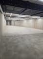 Empty concrete floor, metal beams, pipes, lights, door