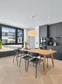 dining area with wooden table, black chairs, kitchen with black cabinets, kitchen island, plant, view of outside