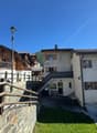 Swiss chalet style house, large wooden balcony, raised ground floor, wooden fencing, garden