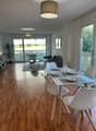 modern dining room with white chairs, wooden floor, dining table, open balcony, glass door