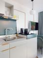 Open plan kitchen, gas stove, stainless steel sink, extractor fan, television, chairs, radiator, windows