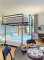 Bunk bed, dining table, armchair, radiator, ceiling lamp, round mirror, window, hardwood floor