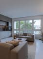 Spacious living room with two sofas, coffee table, mounted TV, large windows with trees view