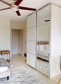 Bedroom with a bed, pillows, nightstand, ceiling fan, a closet with a mirror, a dining table with chairs, a pot plant, breakfast items