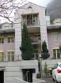 3 story house, pink and yellow painted, ground floor parking, balcony