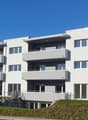 4 story building, white exterior, modern design, several balconies