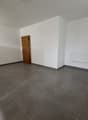 Empty room with white walls, a wooden door, and a radiator on the wall. The floor is covered with large gray tiles.