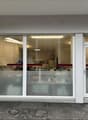 Commercial building with glass facade, white walls, two glass doors, and a small concrete planter.