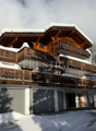 Modern mountain chalet, snow covered, wooden balconies, two garages
