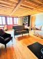 wooden floor, wooden beams, fireplace, sofa, couch, chair, table, bookshelf, painting