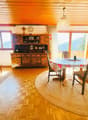 wooden floor, wooden ceiling, dining table, chairs, round rug, wooden cabinet, TV, clock, windows, mountains view