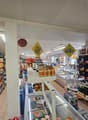 A grocery store with various products on shelves, including snacks, beverages, and condiments. There are also bottles of wine on the shelves.