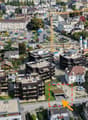 Aerial view of an urban area, residential buildings, a construction crane, and cars parked in lots