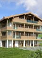 3 story house, wooden exterior, multiple balconies, stone wall foundation, garden, mountain view
