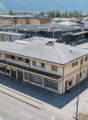 2 story building, gray roof, multiple windows, located in a city