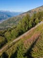 A small chalet on a hill with view of valley and mountains.