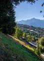 hillside path, grassy area, trees, village houses, mountains in background