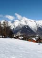Winter mountain scenery, houses, snow-covered mountains, ski lift, clear blue sky