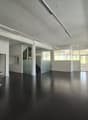 empty room with black floor, three stools, fire extinguisher, large windows, white walls