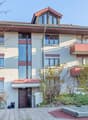 2 story house, white walls, red trim, multiple balconies, garden, entrance with awning