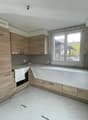 Wooden cabinets, white walls, white tiled floor, open window, under-construction.