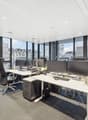 modern office setup with desks, chairs, monitors, office equipment, large windows with city view