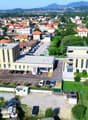 Large building with multiple car parks in front and to the sides, surrounded by trees and hills