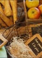 Various fresh produce including parsnips, apples, potatoes, leeks, and lemons in baskets with wooden labels